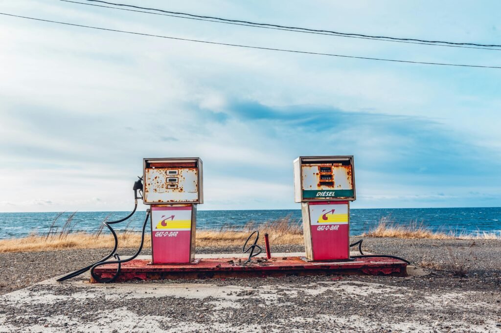 Vintage gas pumps on a deserted seashore with a clear sky and ocean view.